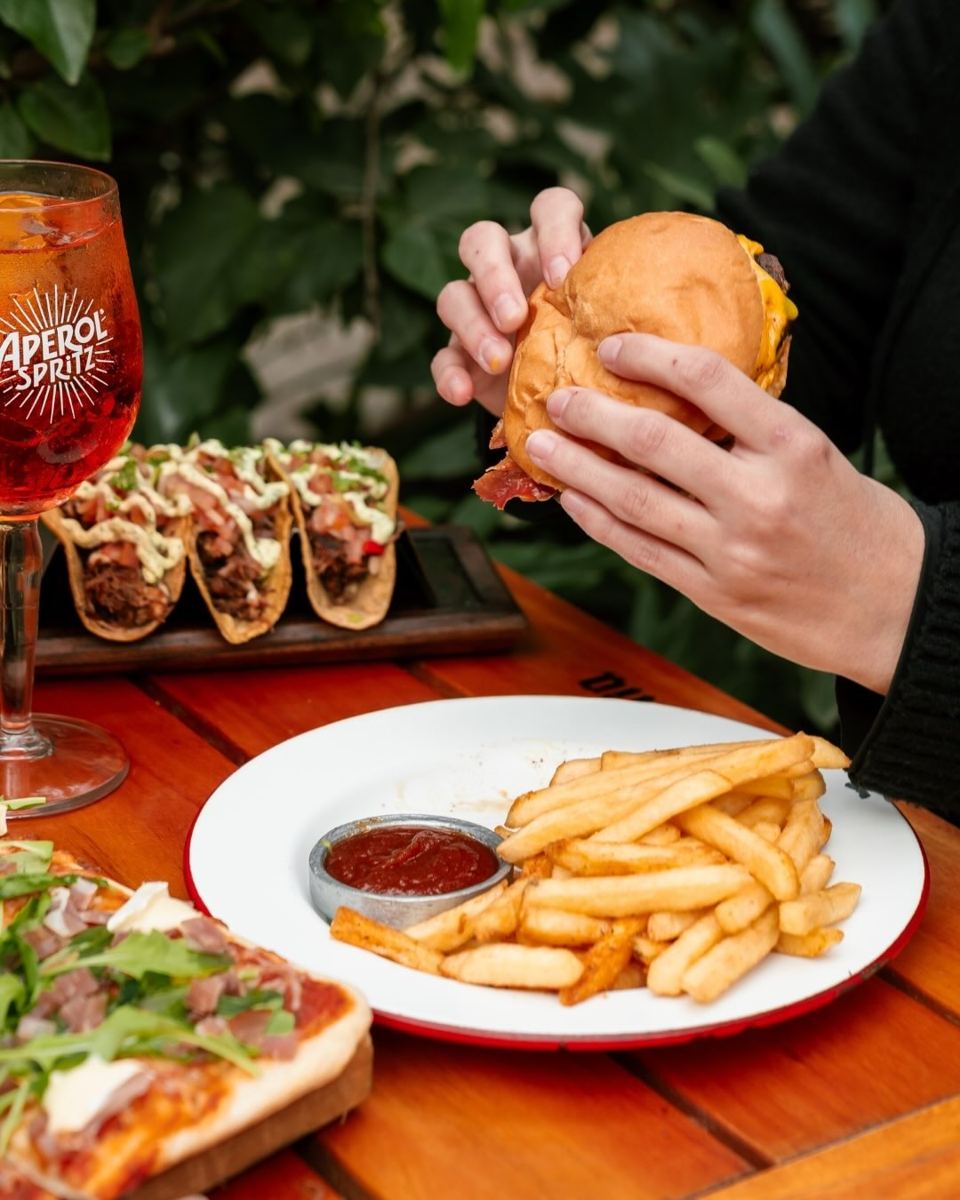 Mesa con burger, tacos y Aperol